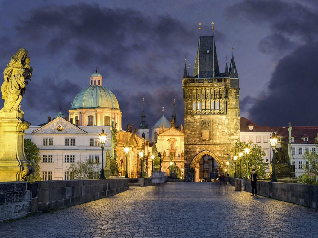 Charles Bridge at dusk, showcasing Prague's illuminated historic architecture.