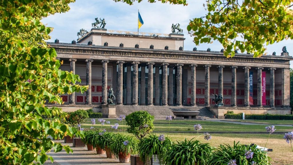 Altes Museum's neoclassical columns flying Ukraine's flag, an educational landmark for study trips.