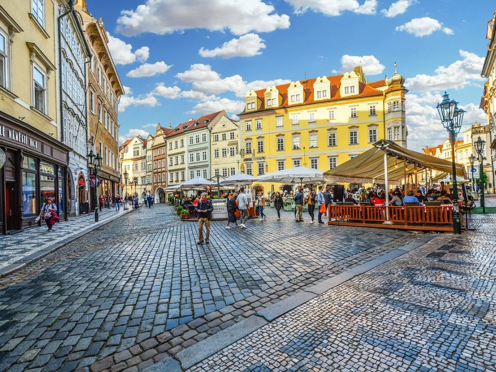 Colorful buildings and cafés in Prague's cobblestone Old Town.