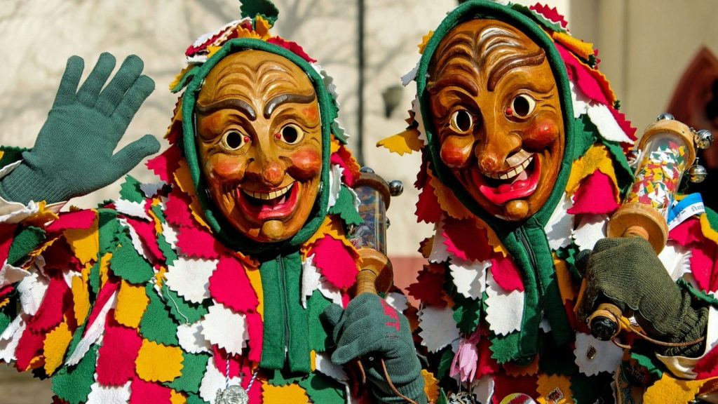 Masked carnival performers in colourful patchwork costumes.